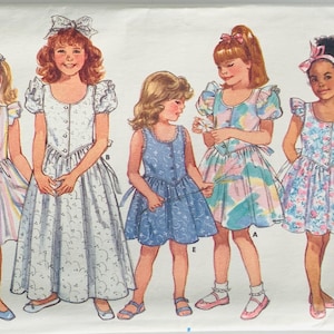 May include: Vintage Butterick Classics sewing pattern 4885 featuring illustrations of five young girls in various dresses. The dresses include striped, floral, and solid blue designs, with details like puff sleeves and bows. The pattern is for sizes 5-6X.