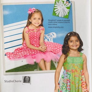 May include: Simplicity sewing pattern 1821A featuring two young girls wearing dresses. The pattern includes sizes 3, 4, 5, 6, 7, and 8. The image includes the text "Simplicity create-it-yourself" and the website address.