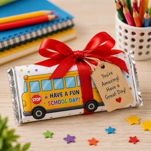 May include: A rectangular candy bar wrapper featuring a yellow school bus graphic with the text HAVE A FUN SCHOOL DAY! and a red stop sign. It is tied with a red ribbon and a brown paper tag that reads You're Amazing! Have a Great Day! with a heart.
