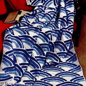 May include: A blue and white crocheted blanket with a wave pattern. The blanket is fringed on all sides.