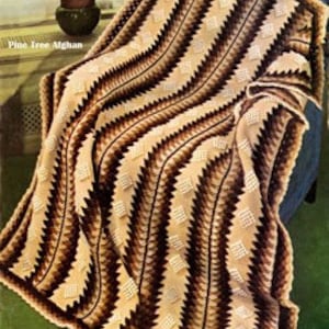 May include: A brown, beige, and white crocheted throw blanket with a chevron pattern. The blanket is draped over a chair.
