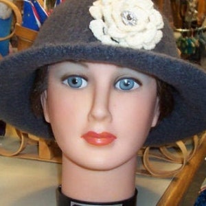 May include: A gray felt hat with a white crocheted flower and a rhinestone embellishment.