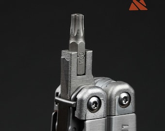 May include: Close-up of a multi-tool with a T30 bit attached. The tool is made of silver metal and has a textured surface. The bit is a star-shaped head. The word "LEATH" is visible on the side of the tool.