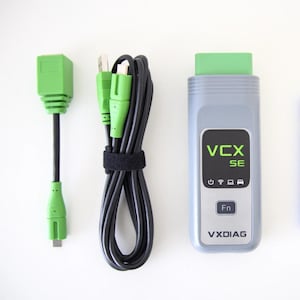 May include: A diagnostic tool set featuring a grey and green device, a green USB cable, and a black cable. The device is labelled with "VCX SE" and "VXDIAG". The set is designed for automotive diagnostics.