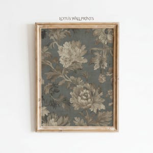 May include: Framed floral print with a vintage aesthetic. The artwork features large, detailed flowers in shades of beige and brown against a dark teal background. The frame is a light, natural wood. The text "LOTUS WALL PRINTS" is at the top.