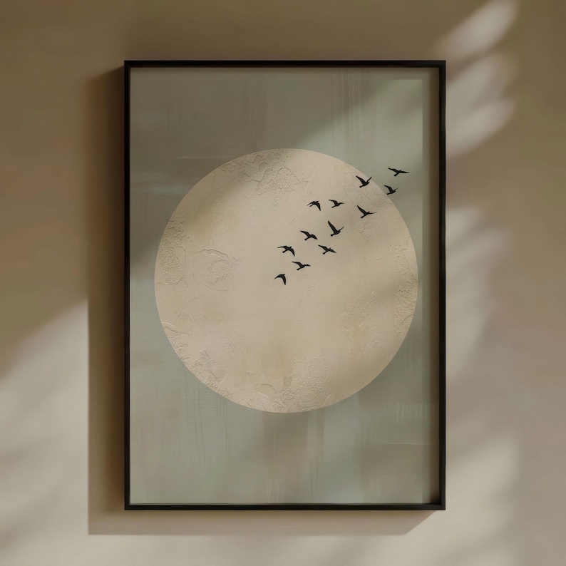 May include: Framed wall art featuring a large, textured, off-white circle against a muted green background. A flock of black birds flies across the circle. The artwork is encased in a black frame, suitable for home decor.