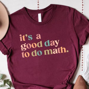May include: A maroon t-shirt with the text "it's a good day to do math." in colorful letters.
