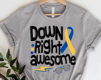 May include: Gray t-shirt with the text "Down Right Awesome" in black. A yellow and blue ribbon is to the right of the text. A lightning bolt and sunglasses are below the text.