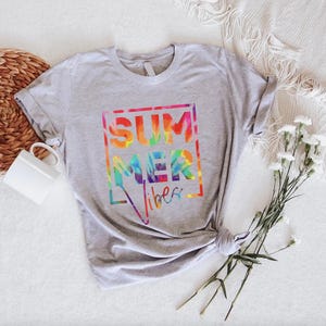 May include: A gray t-shirt with a tie-dye design that says "SUMMER vibes" in a white box.