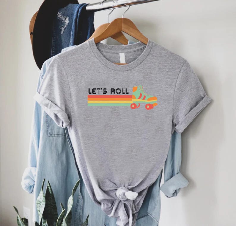 May include: Grey t-shirt with a retro roller skate graphic and the text "Let's Roll" in black.