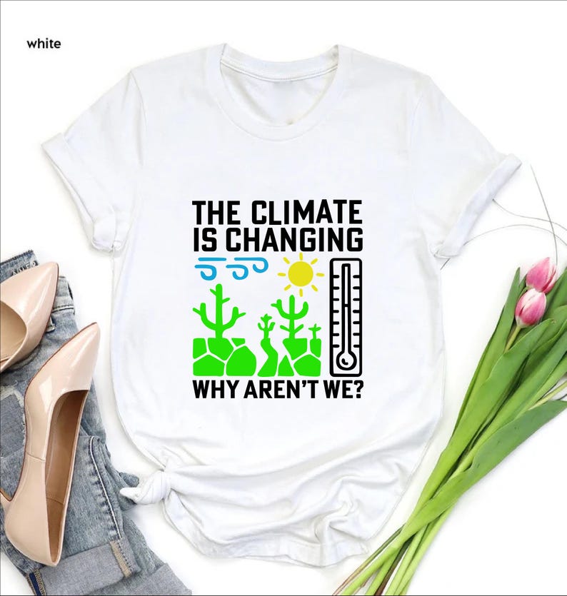 May include: White t-shirt with the text "THE CLIMATE IS CHANGING WHY AREN'T WE?" in black, with illustrations of a sun, thermometer, and cacti in green, blue, and yellow. The shirt is a crew neck.