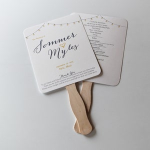 May include: A white wedding fan with a gold and black design. The fan features a string of lights, the text "The Wedding of Sommer Myles", the date "September 16, 2014", and the location "Pa'ia, Maui". The fan also includes the text "Thank You" and a message of gratitude to family and friends.