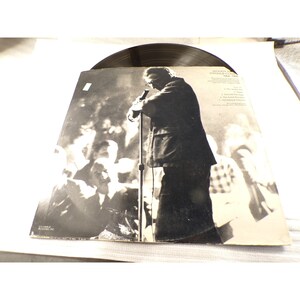 May include: A black and white vinyl record sleeve featuring a photograph of a person standing at a microphone on stage. The text reads Woody Allen Standup Comic 1964-1968, with a track list including The Moose, Marriage, The Great Renaldo, and My Marriage Album.