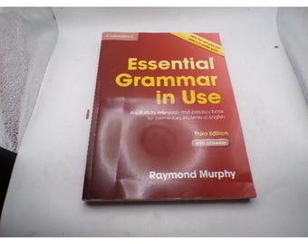 May include: A red and yellow book titled "Essential Grammar in Use" by Raymond Murphy. The book is a study reference and practice book for elementary students of English. The third edition is visible.