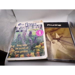 May include: Two gardening books. One is titled "HGTV Flower Gardening" with a photo of a flower garden and the text "Bring home the secrets of great gardens." The other book is titled "Pruning" with a photo of pruning shears.