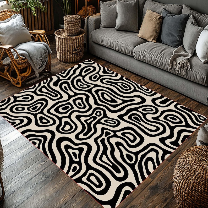 May include: A rectangular area rug with a black and cream-colored abstract pattern. The rug features a repeating design of swirling, organic shapes, creating a bold visual statement. The rug is placed on a wooden floor, adding warmth to the room.