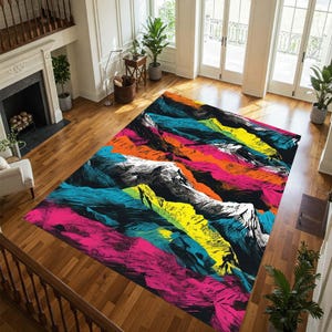May include: A rectangular area rug with a vibrant mountain range design. The rug features a black background with colorful strokes of pink, orange, yellow, and teal, creating a textured effect. The mountain peaks are depicted in grayscale.