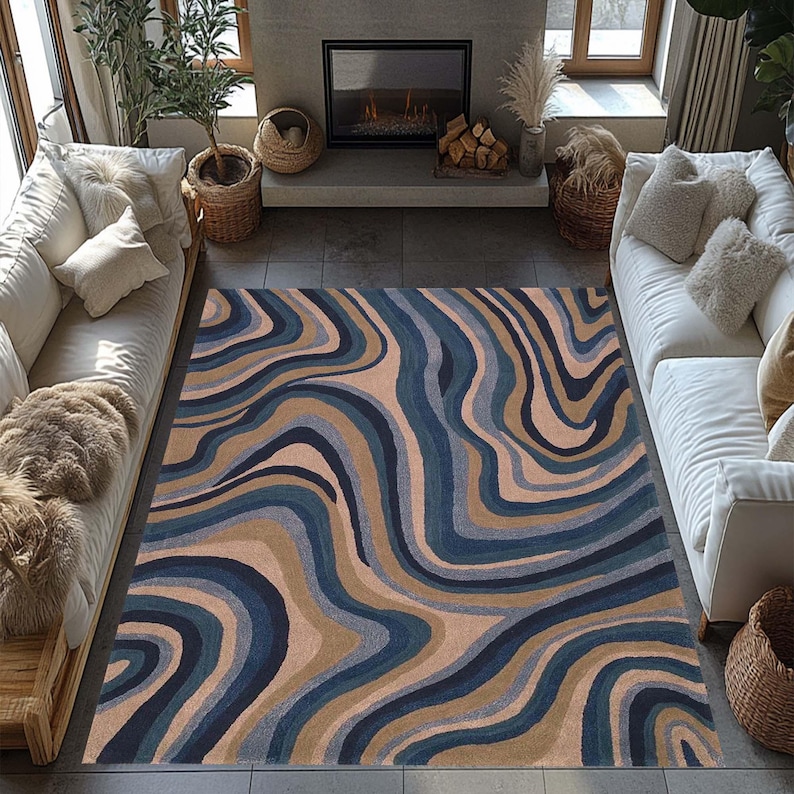 May include: A large area rug with a flowing, abstract design in shades of blue, tan, and brown. The rug's pattern resembles layered waves or geological formations, adding a modern touch to the living room setting.
