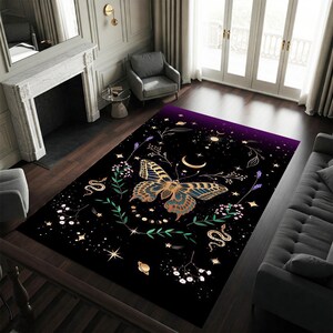 May include: A rectangular black area rug featuring a large butterfly with blue and gold wings, surrounded by celestial and floral elements. The design includes stars, moons, and snakes, with a purple gradient at the top.