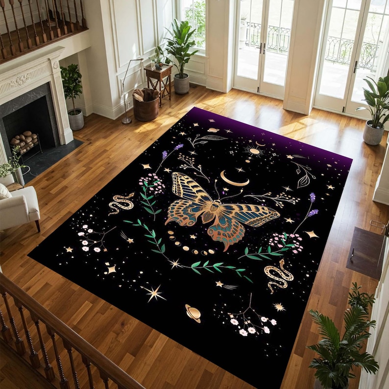 May include: A rectangular black area rug featuring a large butterfly with gold and teal wings. The rug has a celestial design with stars, moons, snakes, and floral elements. The top edge fades to a deep purple.