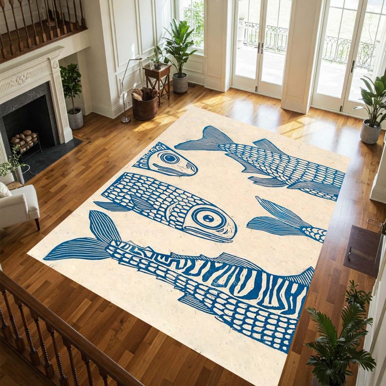 May include: A large rectangular area rug with a cream background and a blue fish pattern. The fish are stylized with detailed scales and fins, creating a nautical or coastal theme. The rug is placed on a hardwood floor.
