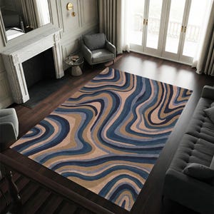 May include: A large area rug with a flowing, abstract design in shades of blue, tan, and beige. The rug's pattern resembles swirling waves or organic shapes, creating a visually dynamic floor covering. The rug is rectangular and appears to be made of a soft material.