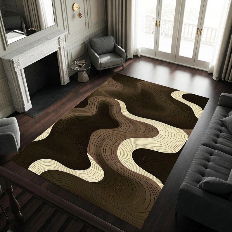 May include: A large area rug with a flowing, abstract design in shades of brown and cream. The rug features a wavy pattern, creating a sense of movement and depth. The rug is placed on a dark wood floor in a living room setting.