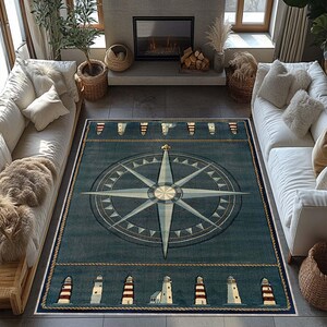 May include: A rectangular nautical-themed rug with a compass rose design in the center. The rug is primarily teal with a cream-colored border and rope-like detailing. Lighthouses are depicted along the edges. The rug is placed in a living room setting.