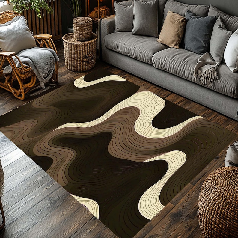 May include: A rectangular area rug with a flowing, abstract design in shades of brown and cream. The pattern features layered, curved lines creating a topographic effect. The rug is placed on a wooden floor, enhancing the warm tones of the design.