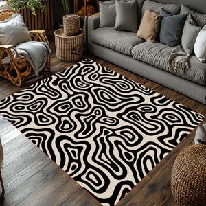 May include: A rectangular area rug with a black and cream-colored abstract pattern. The rug features a repeating design of swirling, organic shapes, creating a bold visual statement. The rug is placed on a wooden floor, adding warmth to the room.