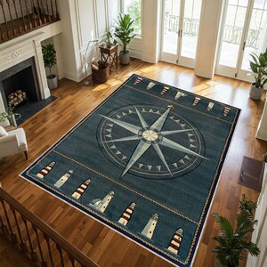 May include: A rectangular navy blue nautical-themed rug featuring a large compass rose design in the center. The rug has a border with lighthouse illustrations and rope detailing. The rug is placed on a hardwood floor.