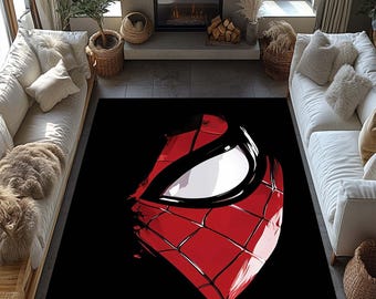 May include: A rectangular black area rug featuring a large, stylized image of Spider-Man's mask. The mask is primarily red with a white eye and black outlining, creating a bold graphic design. The rug is placed in a living room setting.