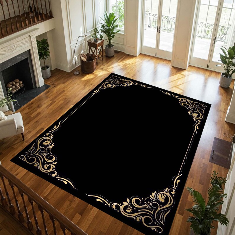 May include: Black and gold area rug with a decorative border of ornate swirls. The rug has a black background with a gold border.
