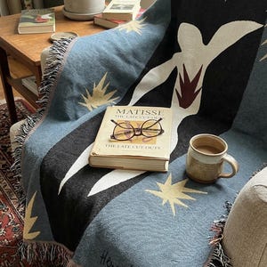 Könnte beinhalten: Ein Set aus drei Keramikbechern mit gesprenkelter, matter Oberfläche. Die Becher sind in Creme-, Hellgrau- und Dunkelgrautönen gehalten. Jeder Becher hat ein schlichtes, minimalistisches Design, ideal für Kaffee oder Tee.