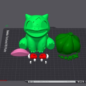 Może przedstawiać: Zielona figurka Bulbasaur wydrukowana w 3D z dużą żarówką na plecach, różowym owalnym kształtem i dwoma czerwono-białymi przedmiotami. Figurka znajduje się na ciemnoszarej powierzchni.