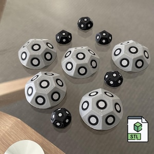 May include: A selection of 3D-printed geometric forms in grey and black. The grey shapes feature large, circular black accents. The black shapes are smaller with white accents. An STL file icon is also present.
