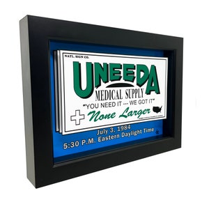 Puede incluir: Una imagen enmarcada de un letrero vintage para una tienda de suministros médicos llamada "UNEEDA". El letrero es blanco con letras verdes y una bandera estadounidense roja y blanca. El texto en el letrero dice "NATL. SIGN CO. UNEEDA MEDICAL SUPPLY "YOU NEED IT --- WE GOT IT" None Larger July 3, 1984 5:30 P.M. Eastern Daylight Time"