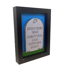 May include: A black framed print of a tombstone with the text "Everything was beautiful, and nothing hurt" on a blue background.