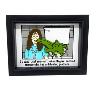 May include: A framed illustration of a cartoon girl vomiting green goo into a toilet. The caption reads "It was that moment when Regan realized maybe she had a drinking problem."