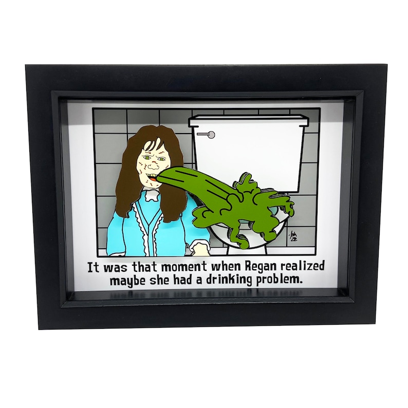 May include: A framed illustration of a cartoon girl vomiting green goo into a toilet. The caption reads "It was that moment when Regan realized maybe she had a drinking problem."