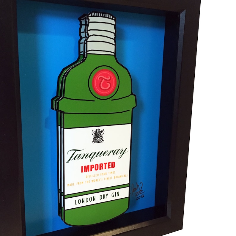 Puede incluir: Una ilustraci&oacute;n enmarcada de una botella de ginebra Tanqueray verde con un sello rojo y el texto "IMPORTED" y "LONDON DRY GIN".