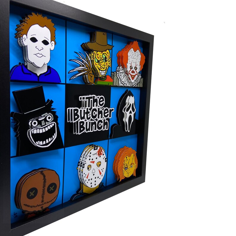May include: A black framed shadow box with a blue background and various horror movie characters. The characters include Jason Voorhees, Freddy Krueger, Michael Myers, Ghostface, and Chucky. The title "The Butcher Bunch" is written in white letters on a black background.