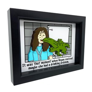 May include: A framed 3D illustration of a cartoon character vomiting green goo into a toilet. The caption reads "It was that moment when Regan realized maybe she had a drinking problem."