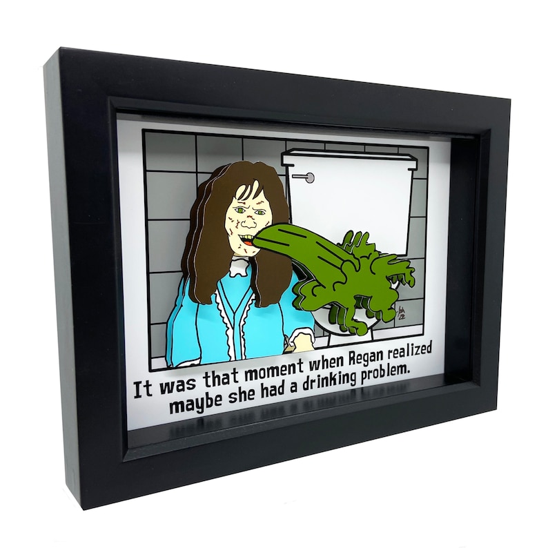 May include: A framed 3D illustration of a cartoon character vomiting green goo into a toilet. The caption reads "It was that moment when Regan realized maybe she had a drinking problem."