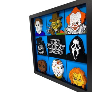 May include: A black framed picture with a blue background and a grid of 9 squares. Each square features a different horror movie character, including Freddy Krueger, Jason Voorhees, Michael Myers, and Ghostface. The title "The Butcher Bunch" is in the center of the grid.