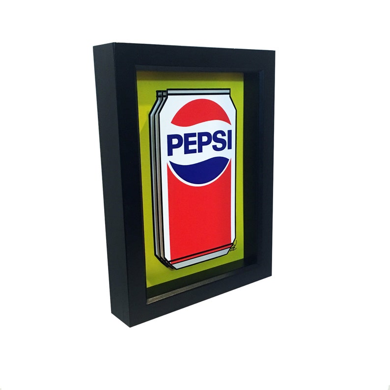 May include: A framed illustration of a red and white Pepsi can on a yellow background. The can has the Pepsi logo in blue and white.