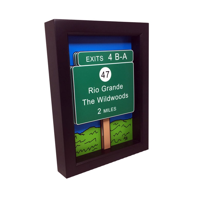 May include: A framed illustration of a green highway sign with the text "EXITS 4 B-A", "47", "Rio Grande", "The Wildwoods", and "2 MILES". The sign is set against a blue sky and green grass background.