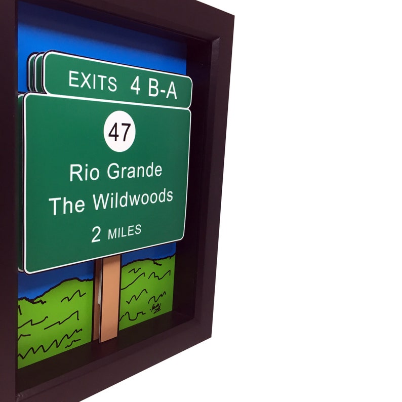May include: A framed illustration of a green highway sign with the text "EXITS 4 B-A", "Rio Grande", "The Wildwoods", and "2 MILES". The sign also has a white circle with the number "47" inside. The sign is set against a blue sky and green grass background.