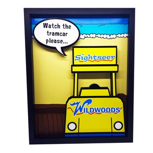 Peut inclure: Une illustration encadr&eacute;e en jaune et bleu d'un tramway jaune avec les mots "Sightseer" et "Wildwoods" dessus. Le tramway est sur une plage avec un ciel bleu et des vagues blanches. Une bulle de dialogue au-dessus du tramway dit "Regardez le tramway s'il vous pla&icirc;t..."