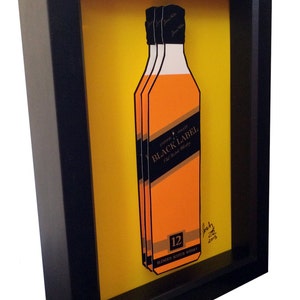 K&ouml;nnte beinhalten: Ein gerahmtes Kunstwerk mit einer 3D-Illustration einer Flasche Johnnie Walker Black Label 12 Jahre alter Blended Scotch Whisky. Die Flasche ist orange und schwarz mit dem Text "Johnnie Walker Black Label" und "12" darauf gedruckt. Das Kunstwerk ist vor einem gelben Hintergrund platziert und mit "Josh 2015" signiert.